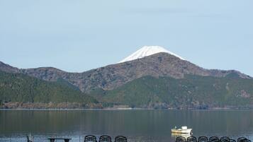 A lake with a boat, metal chairs, and a mountain in the background.