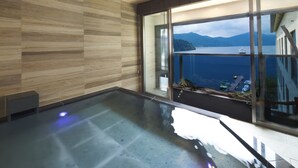 A modern interior with a large glass window offering a view of a lake and mountains. - Hakone Hotel (Hakone)