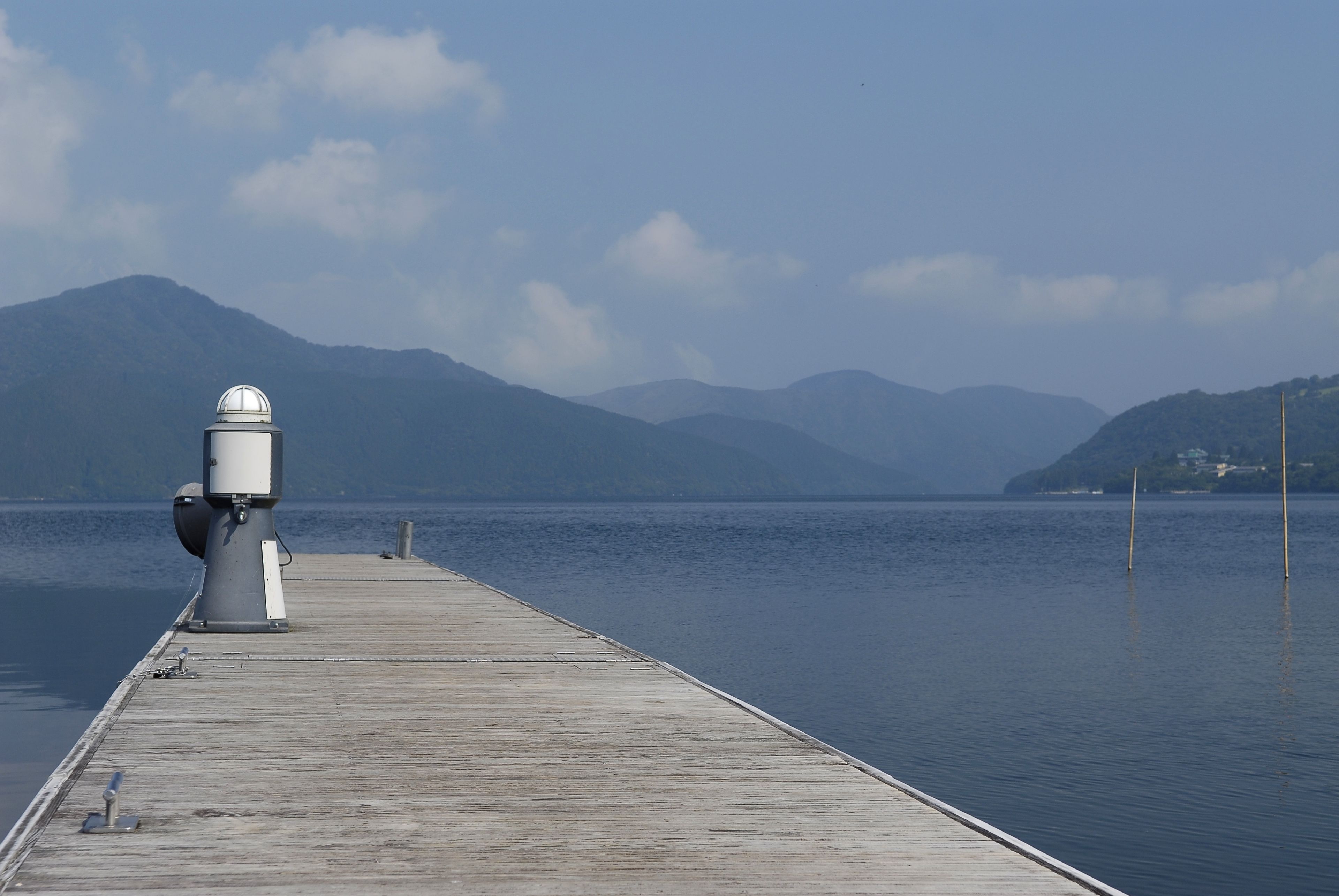 Un muelle de madera que se adentra en aguas tranquilas, con un telescopio a la izquierda.
