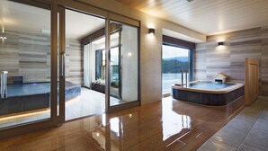 Un moderno espacio de spa con una bañera de hidromasaje, puertas de vidrio que dan a un balcón y vistas al exterior.