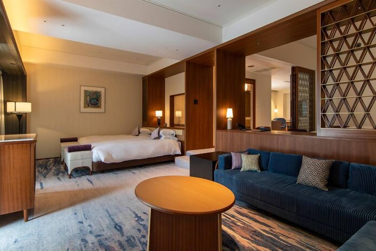 Et hotelværelse med en seng, en sofa, et lille bord og en dekorativ vægpanel.