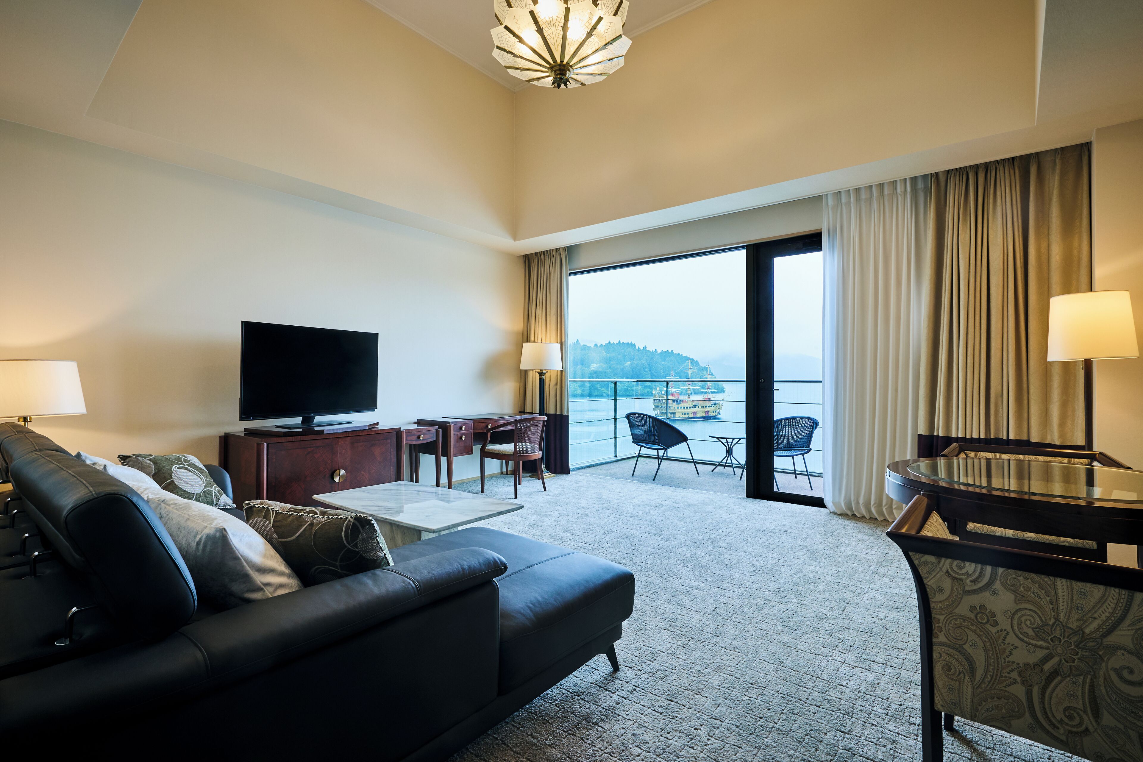 Een hotelkamer met een groot bed, een televisie, een bureau en een balkon met uitzicht.
