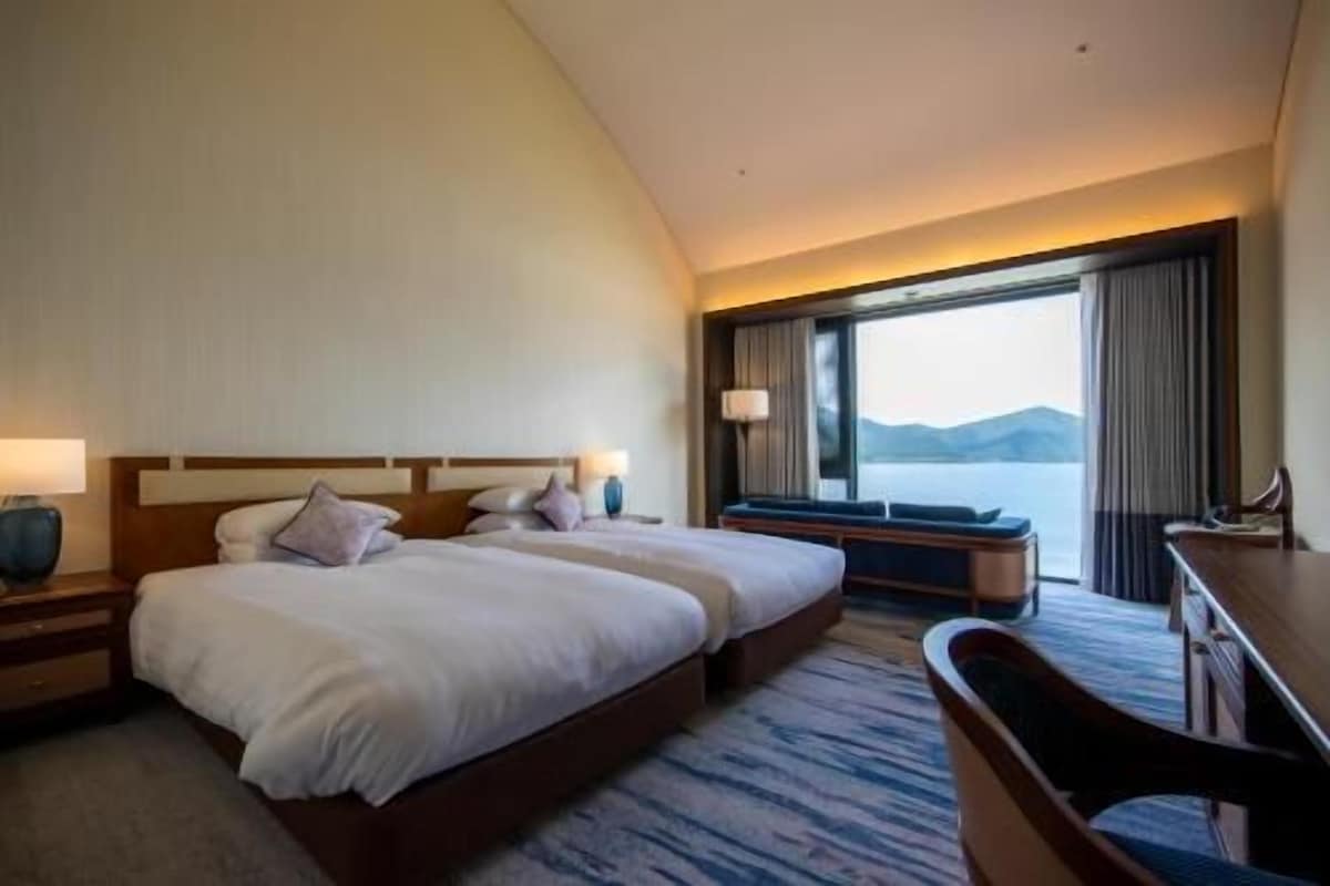 A hotel room with a large bed, a desk, and a view of the water.