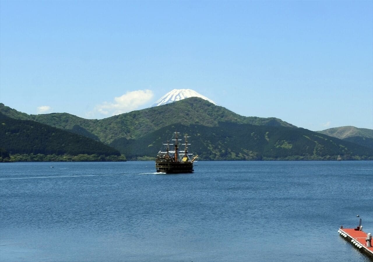 Un navire sur une étendue d’eau calme, avec une montagne en arrière-plan.