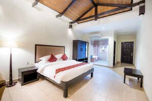 A modern hotel room with a large bed, a bedside table, a floor lamp, and a wardrobe.