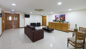 A modern living room with a brown sofa, a coffee table, a TV, and a dining area with a table and chairs. - Matiz Barão Geraldo Express (Campinas)