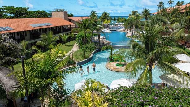 A resort with a central pool, palm trees, and a view of the ocean. - Salinas Maceió All Inclusive Resort (Maceió)