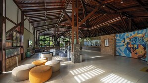A spacious lobby with a high ceiling, large windows, and a colorful mural. - Salinas Maceió All Inclusive Resort (Maceió)