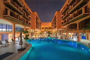 Una piscina al aire libre, sombrillas, sillones reclinables de piscina