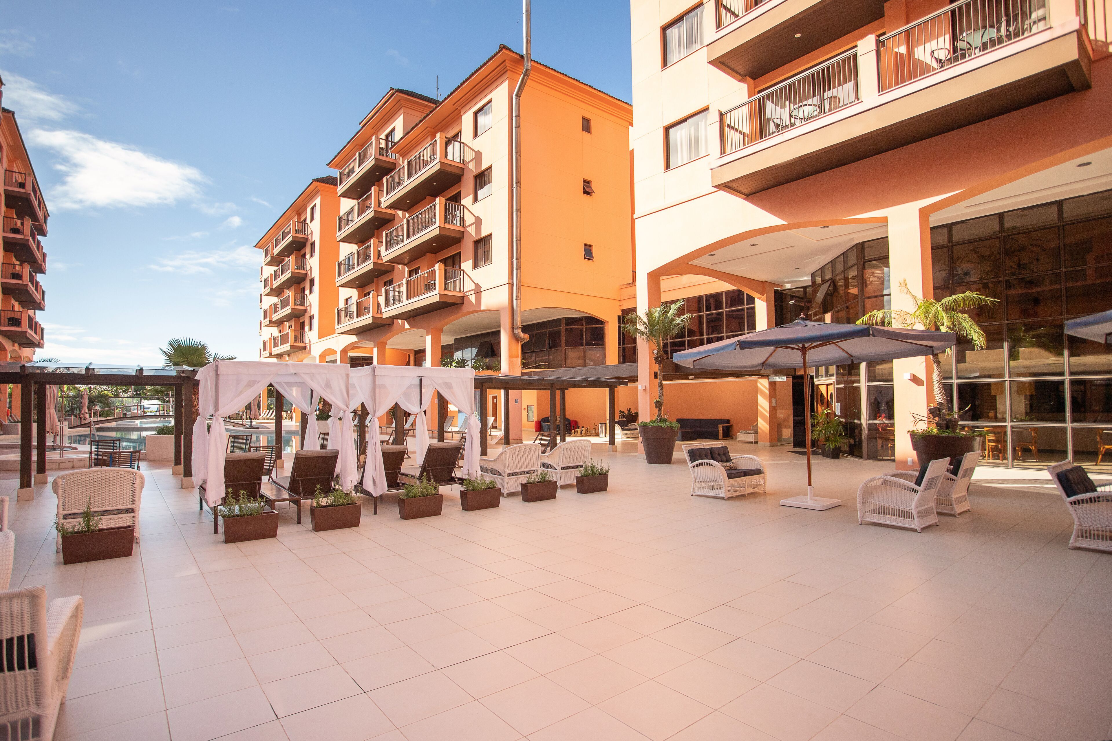 A hotel courtyard with outdoor seating, a pool, and multiple balconies.