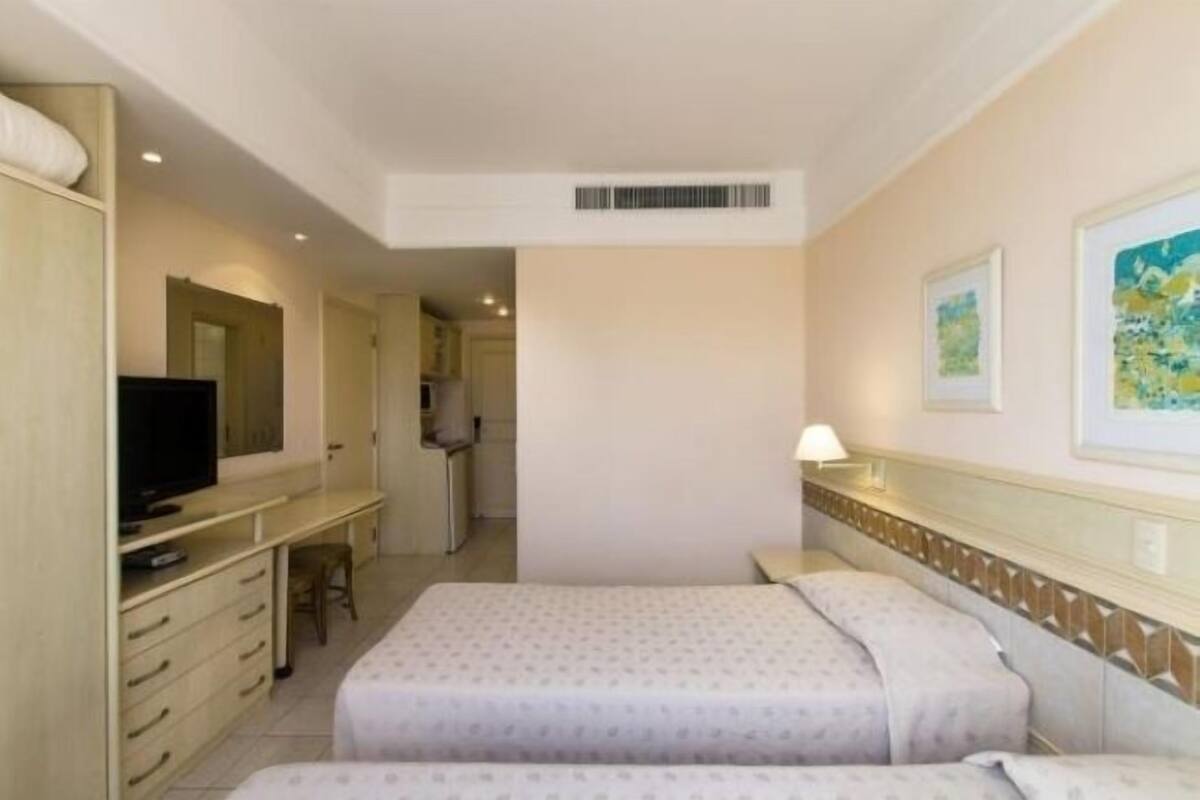 Ein Hotelzimmer mit einem Bett, einem Schreibtisch mit Fernseher und einem Sessel.