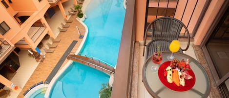 A pool area with a curved design, surrounded by a multi-story building with balconies.