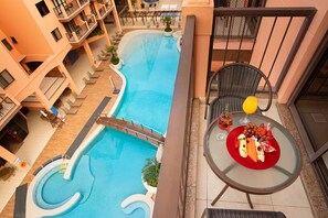 A pool area with a curved design, surrounded by a multi-story building with balconies. - Hotel Jurerê Beach Village - OFICIAL (Florianópolis)