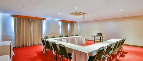 A conference room with a long table, green chairs, and a red carpet.