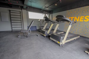 Un gimnasio con cintas de correr, una bicicleta estática y un banco de pesas.