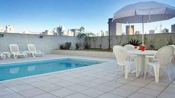 Una piscina al aire libre, sombrillas, sillones reclinables de piscina