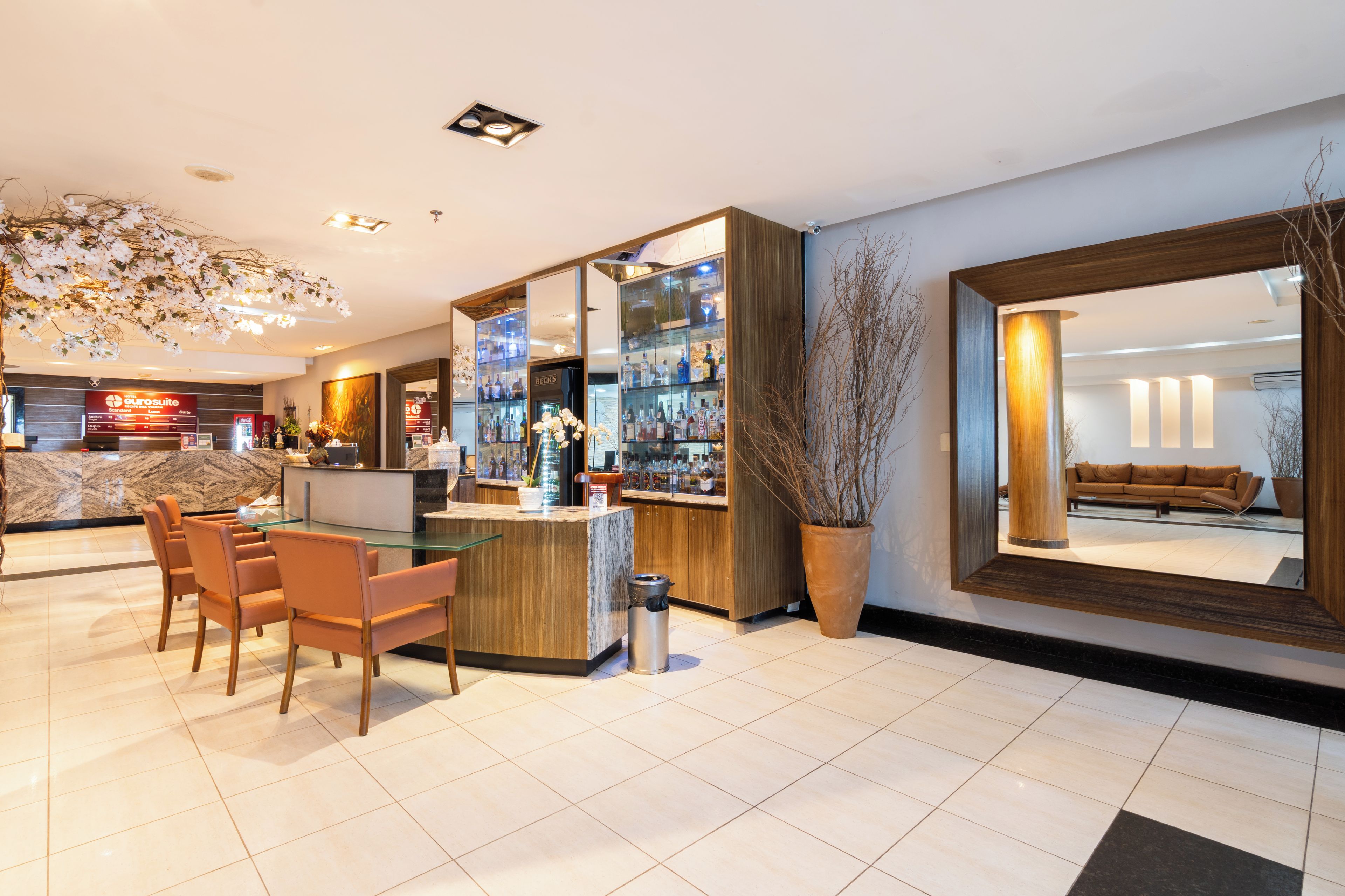 A hotel lobby with a reception desk, seating area, and a bar.
