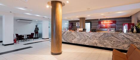 En hotellobby med en marmordisk, en stor pelare och en sittgrupp.