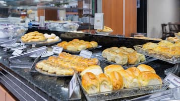 Un bufé con diversas opciones de panadería expuestas en recipientes de vidrio.