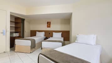 Habitación de hotel con dos camas individuales, cabecero de madera, un cuadro pequeño en la pared y un armario con puertas correderas.