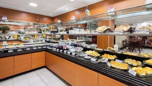 A buffet with various food items, a wooden interior, and a glass display case. - Hotel Euro Suíte Recife By Nacional Inn (Recife)