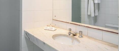 A bathroom with a marble sink, a mirror, and a sign indicating no smoking.