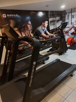 Un gimnasio con cintas de correr y pelotas de ejercicio, que presenta un gran anuncio de 'euro suit'.