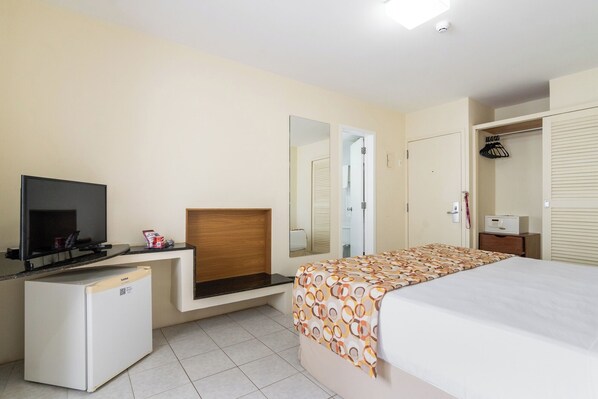 A hotel room with a bed, a TV, a minibar, a mirror, and a wardrobe. - Hotel Euro Suíte Recife Boa Viagem By Nacional Inn (Recife)