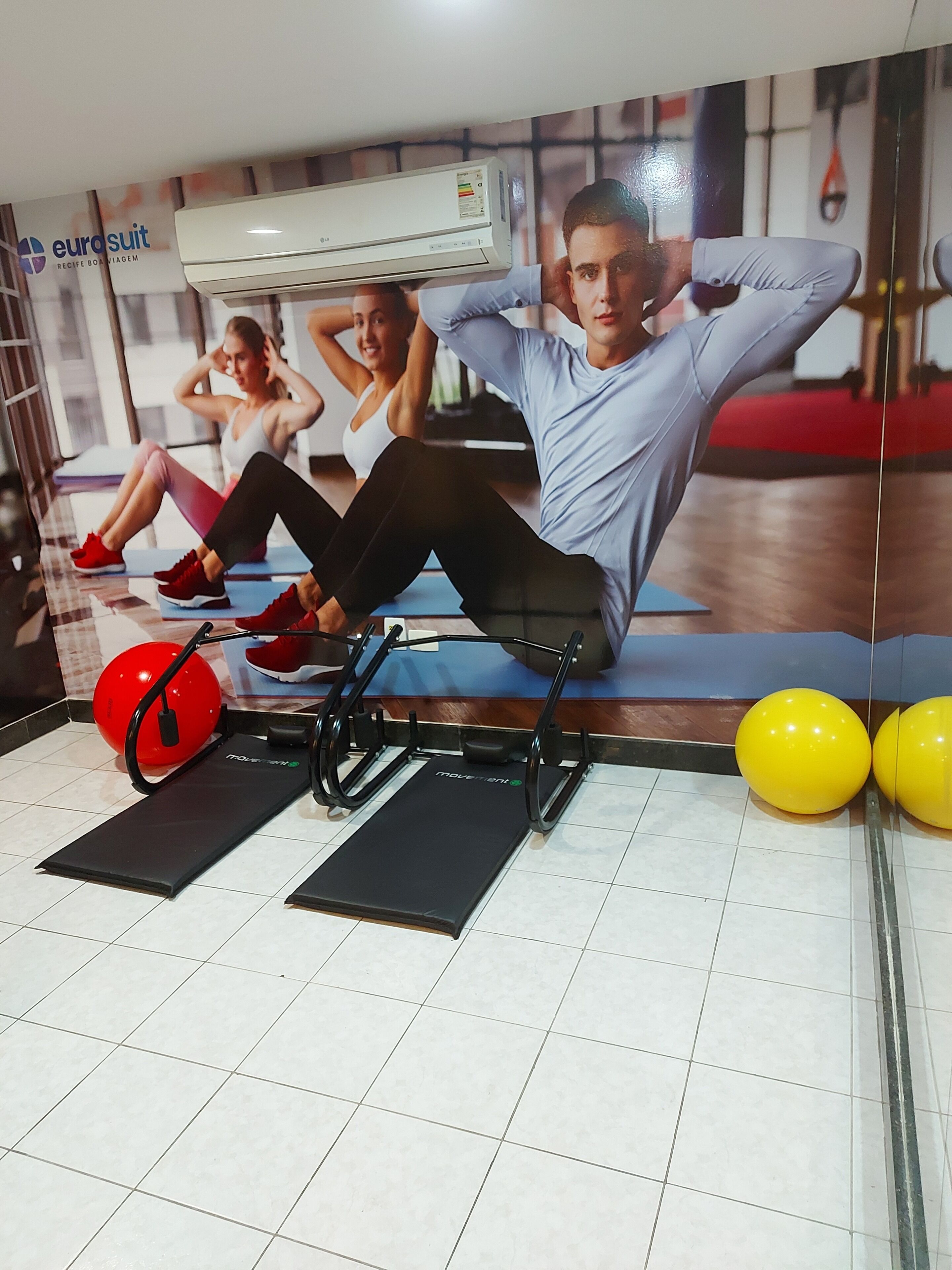 A gym with exercise equipment, a large mirror, and a wall-mounted air conditioner.