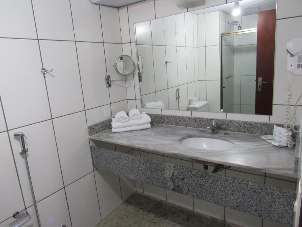 Une salle de bain avec un lavabo en marbre, un grand miroir et un porte-serviettes.