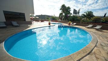 Alberca al aire libre, sombrillas en la alberca y camastros