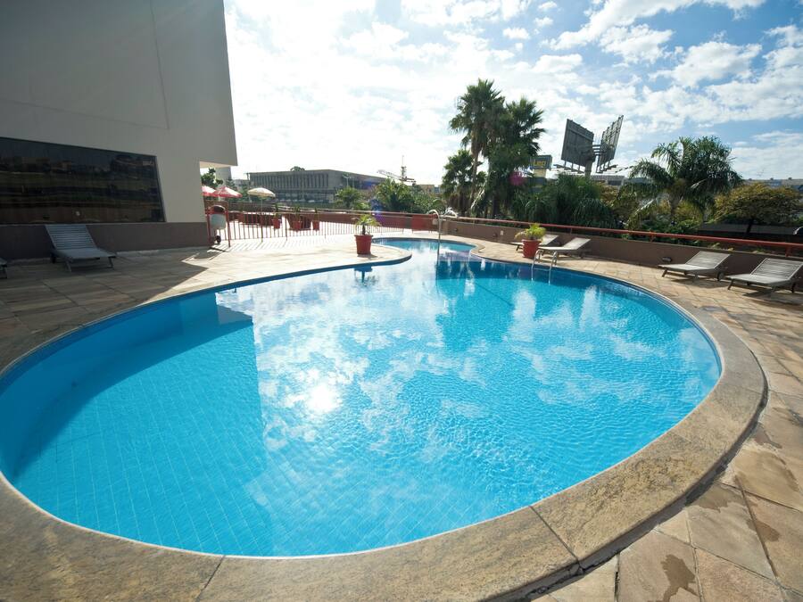 A swimming pool with lounge chairs and palm trees.