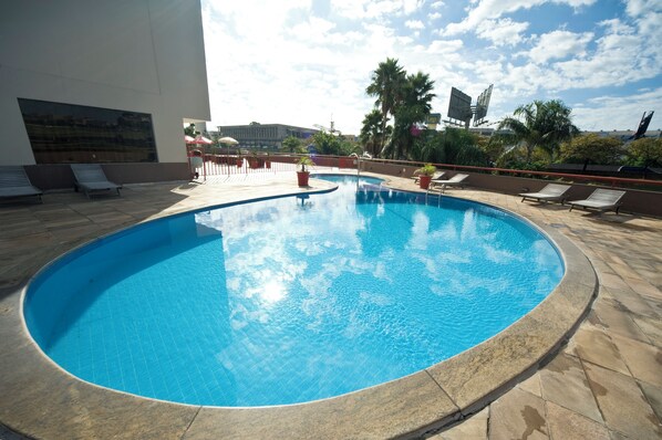 Una piscina con tumbonas y palmeras.