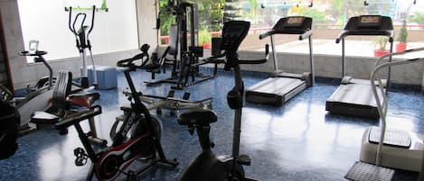 Un gimnasio con equipos de ejercicio variados, incluyendo cintas de correr, bicicletas estáticas y máquinas de pesas.
