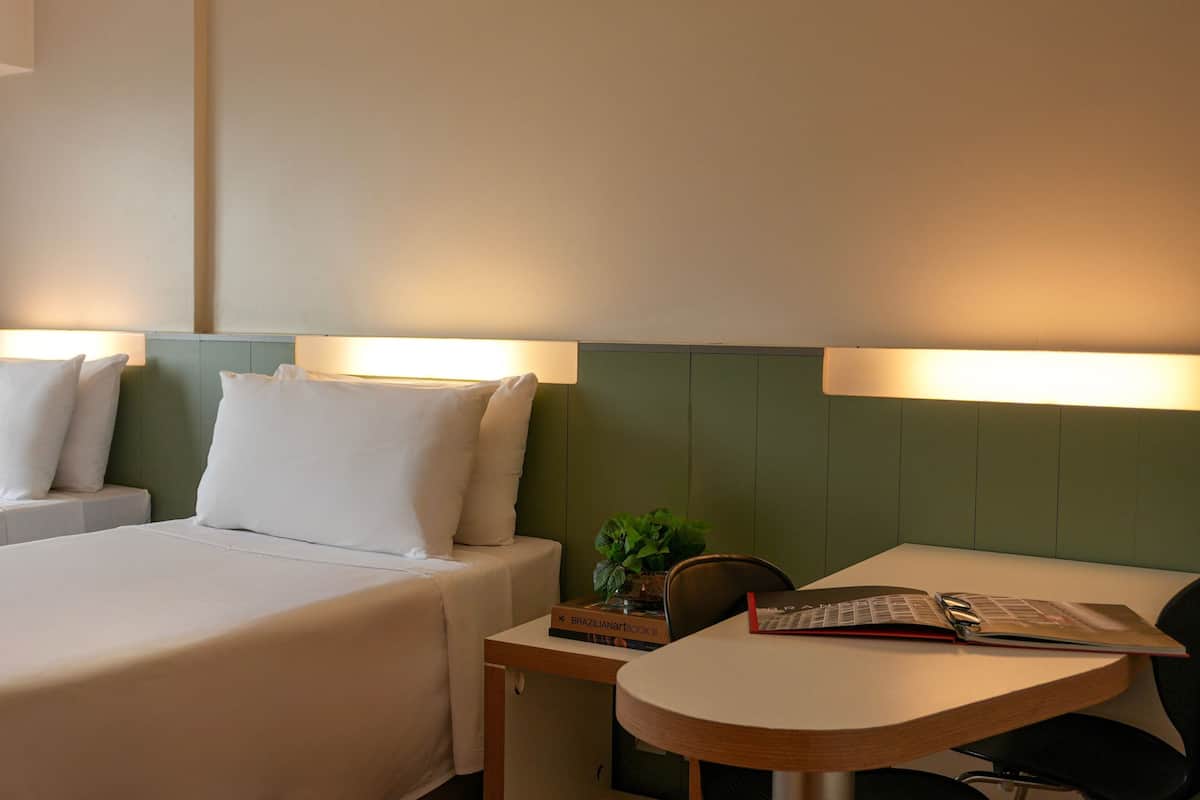 Ein Hotelzimmer mit zwei Betten, einem kleinen Tisch und einem Stuhl.