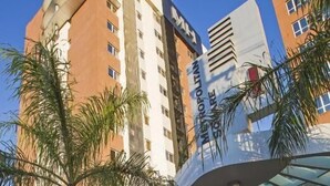 A modern hotel with a distinctive curved glass entrance and a prominent 'Hotel' sign. - Astron Hotel Bauru by Nobile (Bauru)