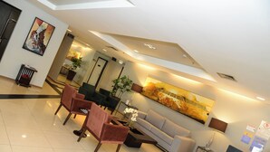 A spacious lobby with a high ceiling, a large painting, and a reception desk. - Astron Hotel Bauru by Nobile (Bauru)