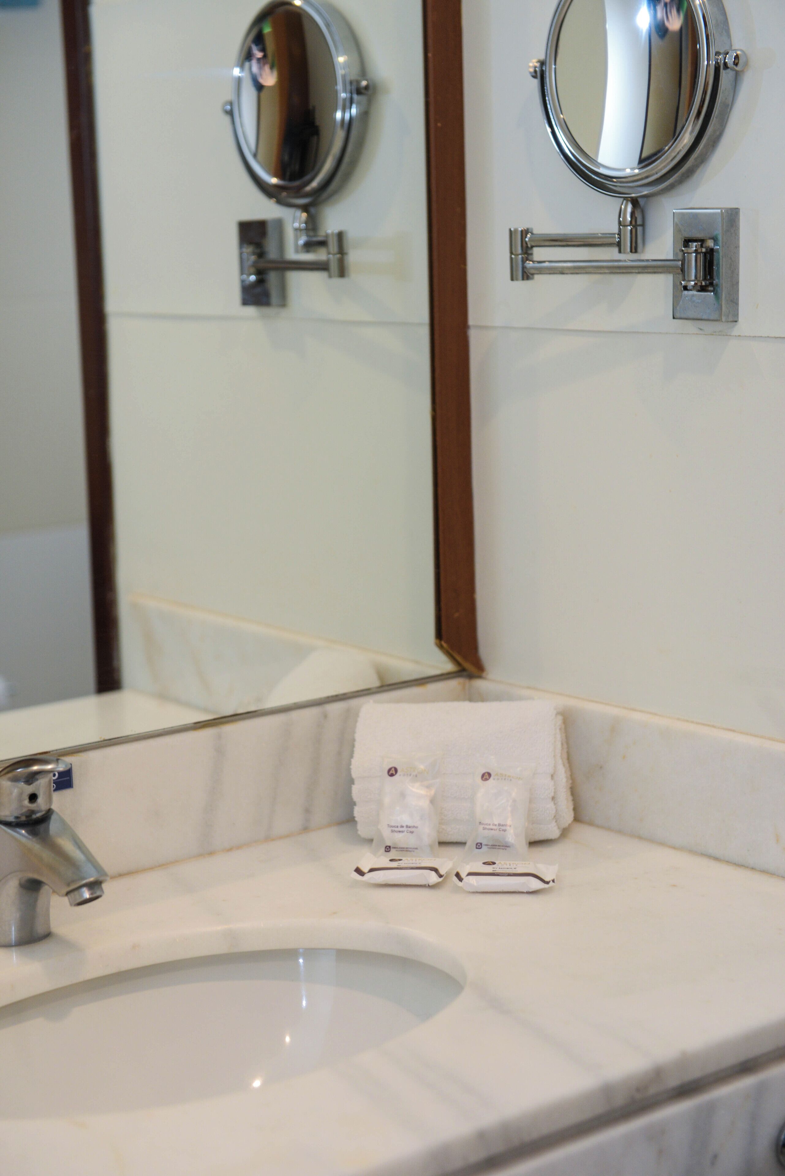 A bathroom with a sink, two mirrors, and a towel rack.