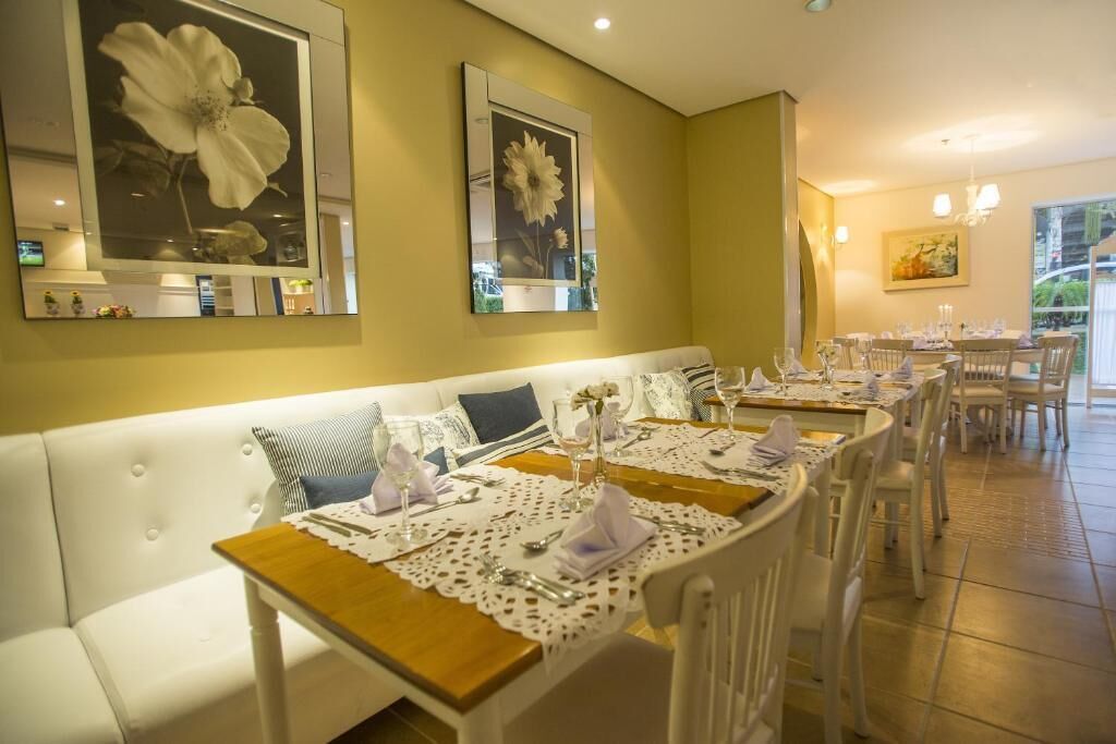 A dining area with white furniture, floral wall art, and a view of the outdoors.