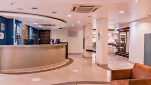 A hotel lobby with a reception desk, seating area, and a dining section. - Master Express Curitiba (Curitiba)