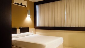 A hotel room with a bed, an air conditioning unit, a wall-mounted light, and a window with curtains. - Master Express Curitiba (Curitiba)