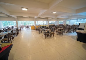 Un amplio comedor interior con varias mesas y sillas, ventanas grandes y una barra central.