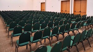 A conference room with rows of green chairs, a carpeted floor, and a ceiling with recessed lighting. - Itapura Eco Resort   (Atibaia)
