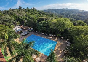 Una piscina circondata da rigogliosa vegetazione e un paesaggio collinare.