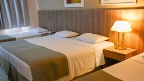 Ein Hotelzimmer mit zwei Betten, einem Nachttisch mit Lampe und einem an der Wand befestigten Telefon.