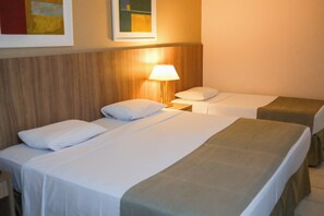 Ein Hotelzimmer mit zwei Einzelbetten, einem Nachttisch mit Lampe und einem Holzkopfende.