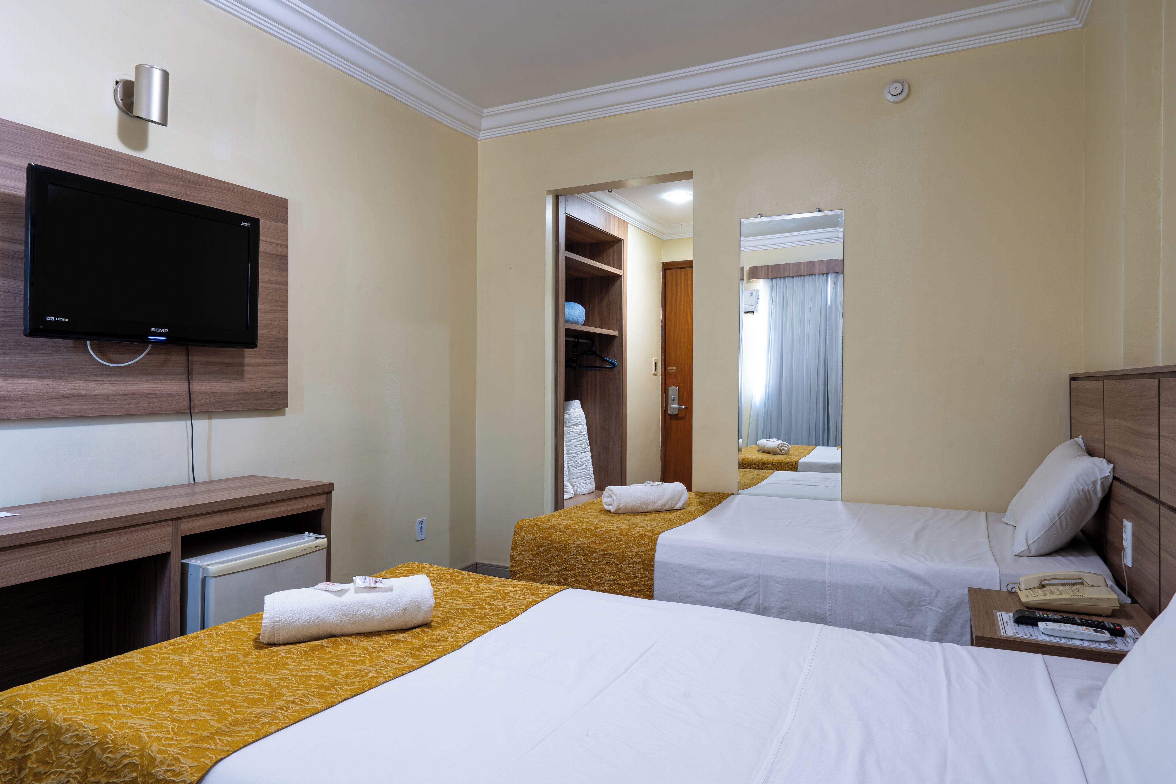 A hotel room with two beds, a TV, a desk, and a wardrobe.