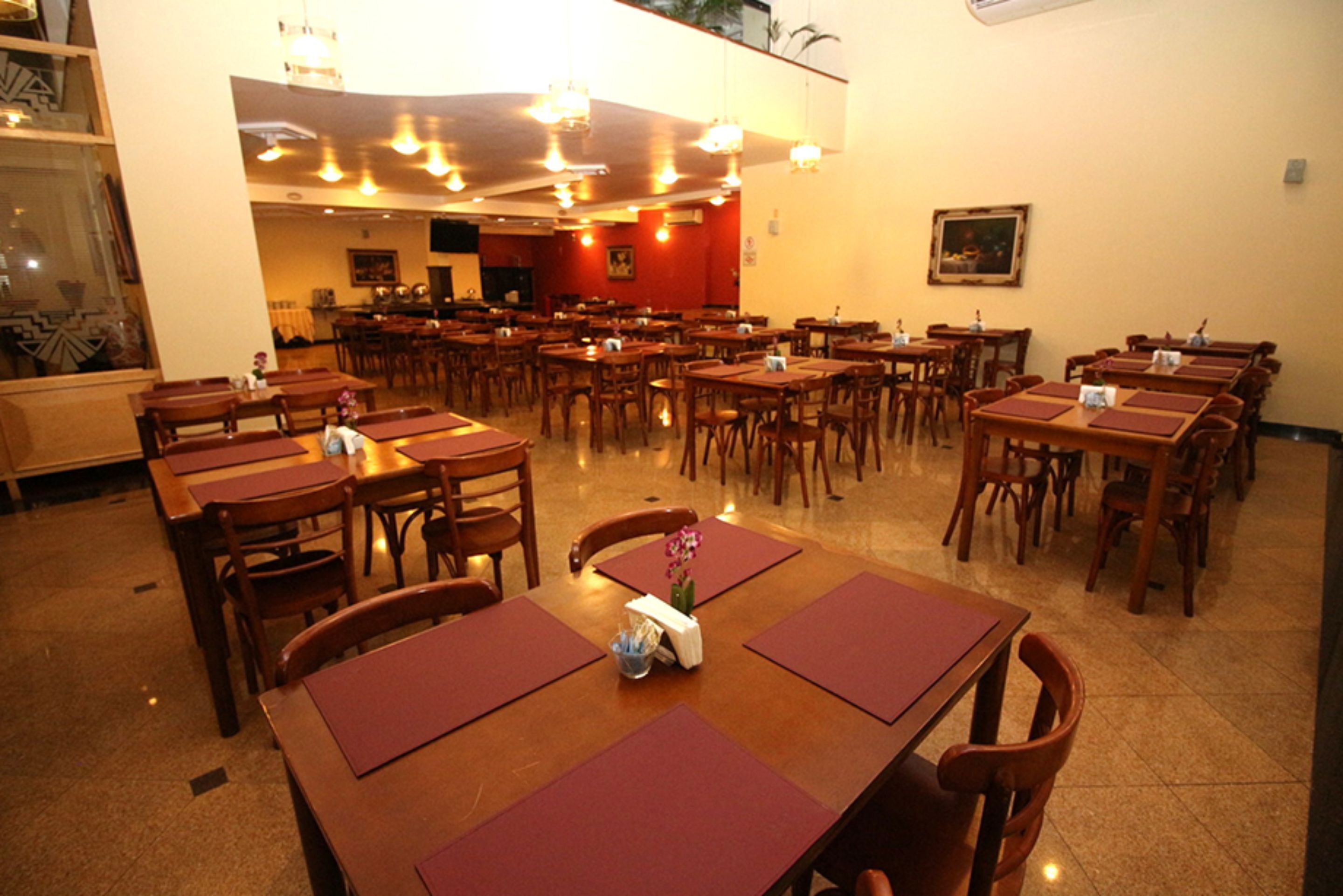 Un restaurant spacieux, doté de nombreuses tables et chaises en bois, disposées dans une grande salle.