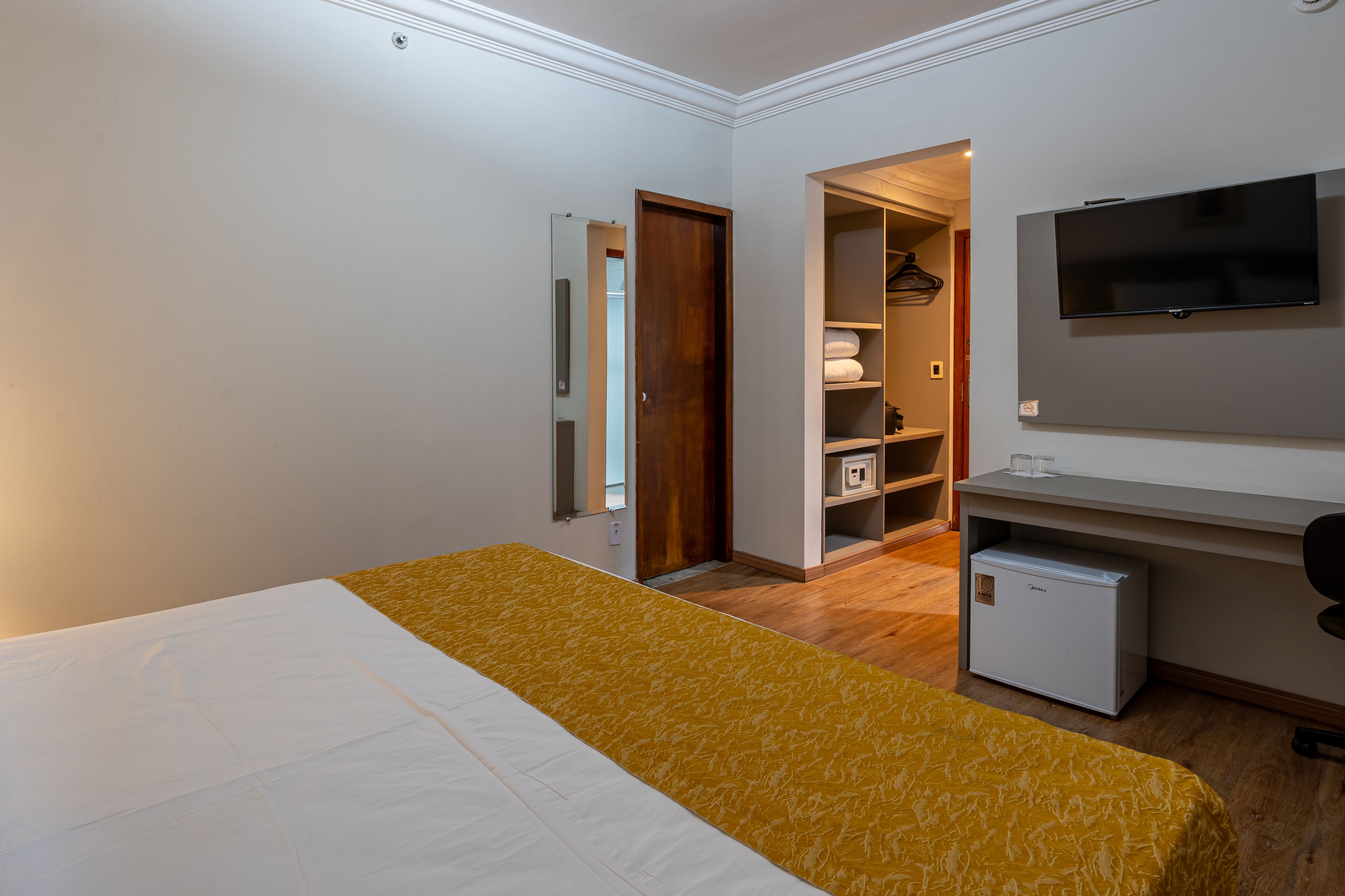 Une chambre d’hôtel équipée d’un lit, d’un bureau, d’une télévision et d’une armoire.