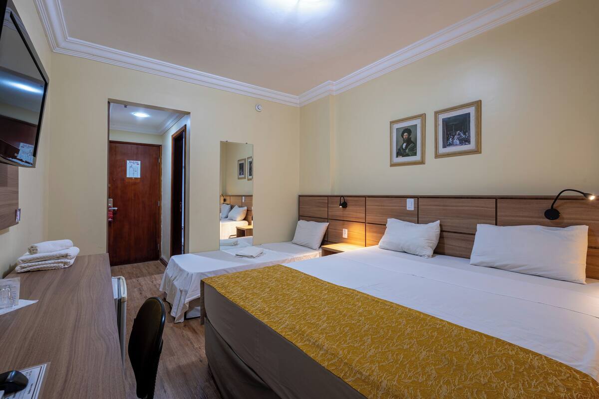 Ein Hotelzimmer mit zwei Betten, einem Schreibtisch, einem Stuhl und einem Fernseher.